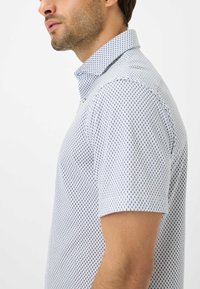 Korte mouwen overhemd met knopen in het wit met een marineblauw stippenpatroon, met een klassieke kraag en een lichte, ademende textuur.