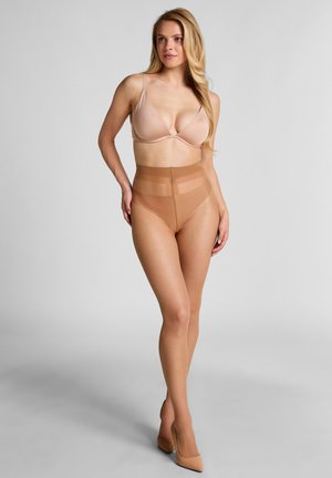 Nuder nahtloser BH und hochgeschnittene Slips mit durchsichtigen oberen Elementen. Glattes Material mit matter Oberfläche. Spitz zulaufende, nudefarbene High Heels ergänzen den Look.