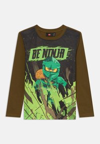 Brązowa koszula z długim rękawem z zielonym i czarnym nadrukiem z przodu przedstawiającym LEGO ninja oraz napisem "BE NINJA" w pogrubionych zielonych literach.