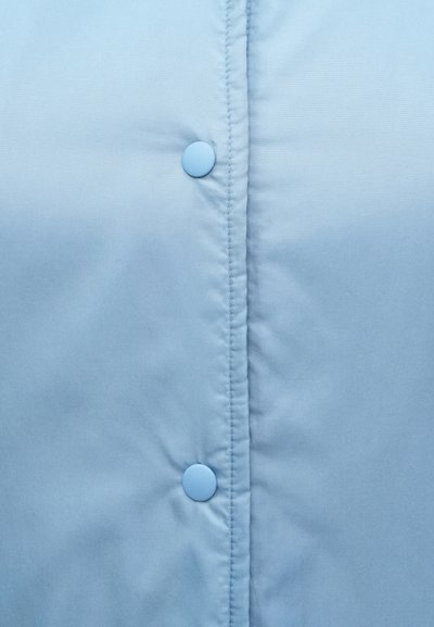 Lichtblauwe gewatteerde jackstof met zichtbare stiksels. Twee ronde blauwe knopen sluiten de voorkant, met een gladde, matte textuur.