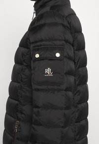 Svart vadderad jacka med en sidficka med guldknappar och Ralph Lauren-logotyp påärmen.