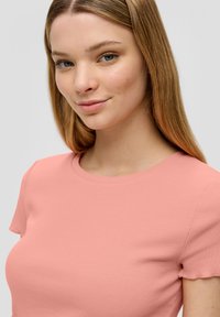 Roze geribd T-shirt met korte mouwen, met een ronde halslijn en zachte textuur. De stof heeft een lichte rek en een aansluitende pasvorm.