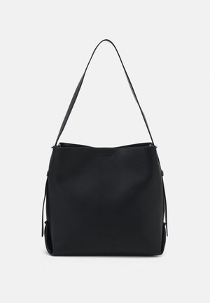 Bolso de hombro de cuero negro con una superficie lisa, correa ancha y diseño minimalista, presentado sobre un fondo claro y sencillo.