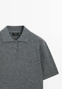 Šedé polo tričko vyrobené z měkkého pleteného materiálu, s klasickým límečkem, třemi knoflíky a krátkými rukávy. Texturovaná tkanina s minimálním vzorem.