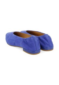 Une paire de ballerines en daim bleu avec de petits talons et des orteils arrondis, présentées de dos sur un fond blanc.