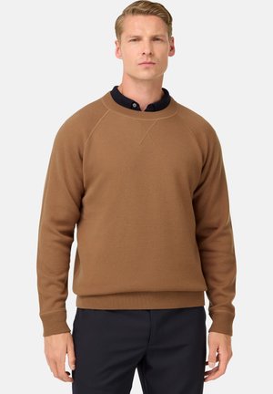 Brauner Sweatshirt mit langen Ärmeln, Rundhalsausschnitt sowie gerippten Bündchen und Saum. Weicher Stoff mit leicht strukturierten Oberfläche. Darunter befindet sich ein navyblaues Hemd mit Kragen.