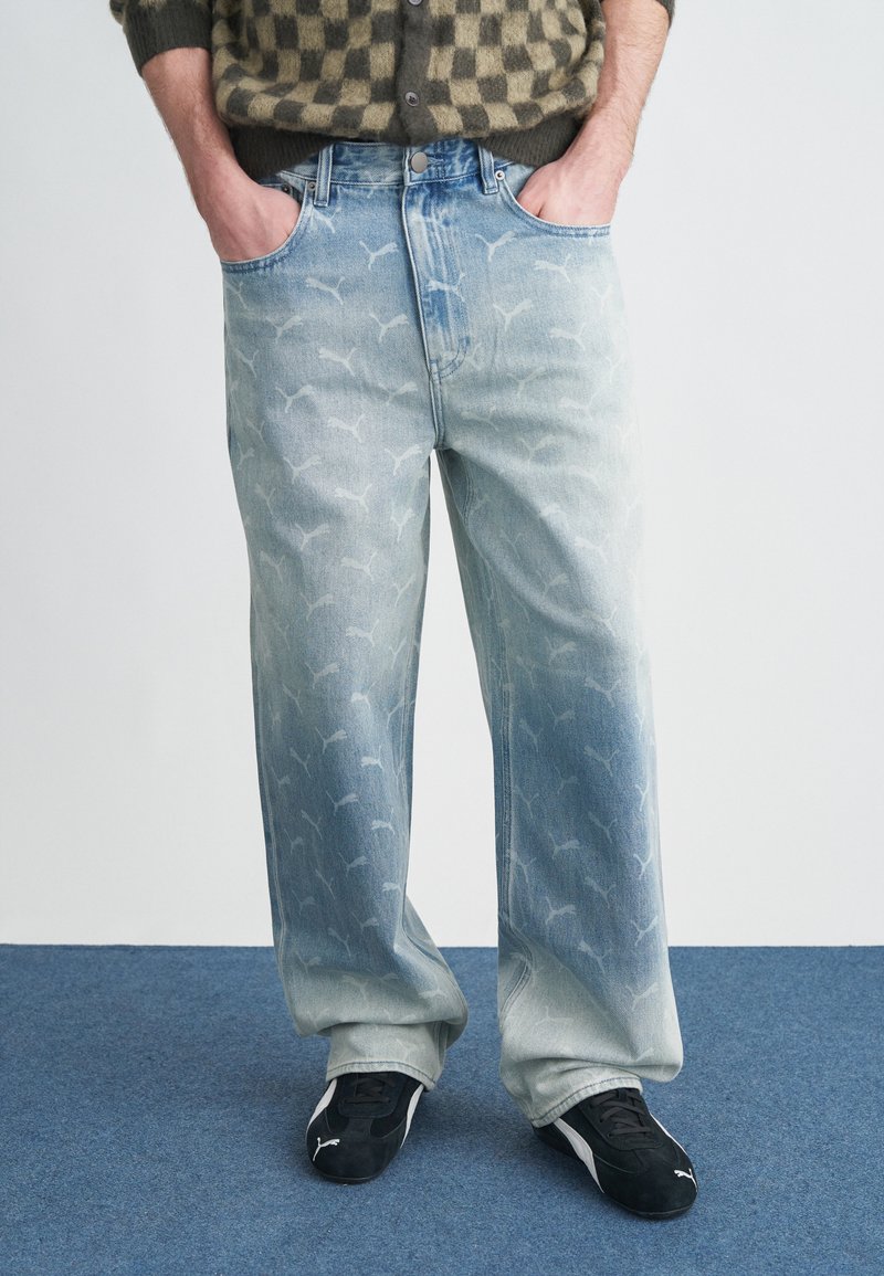 Calças de ganga azul claro com efeito ombre desbotado e padrão branco por toda a peça. Apresentam um design clássico de cinco bolsos e um corte relaxado.