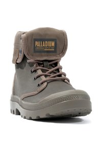 Braune Leinenschuhe mit Gummisohle, mit einem faltbaren Schaft, Metallösen und einem Logo-Patch auf der Zunge. Gepolsterter Kragen für Komfort.