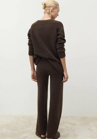 Brauner Strickpullover mit lockerer Passform und gerippten Bündchen, kombiniert mit passenden weit geschnittenen Hosen. Weiche Textur mit einem entspannten Silhouette.