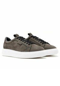 Sneakers in suede grigio con lacci neri, suole di gomma bianche e un design elegante. Presentano cuciture minime e un occhiello sul tallone.