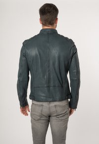 Giacca da motociclista in pelle blu scuro con finitura testurizzata, design slim fit, polsini con zip e dettagli delle cuciture visibili sul retro.