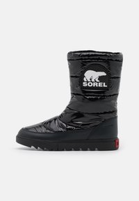 Stivale isolato nero con finitura lucida, parte superiore imbottita e suola in gomma a contrasto con grip testurizzato e patch del logo.