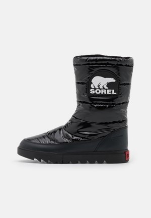 Botte isolante noire avec une finition brillante, un dessus rembourré et une semelle en caoutchouc contrastante avec une texture antidérapante et un patch logo.