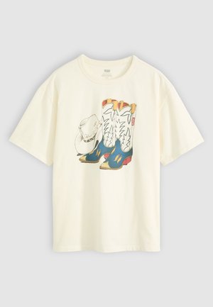 Witte katoenen t-shirt met een afbeelding van cowboylaarzen en een hoed. De laarzen zijn blauw met gele accenten en witte details.