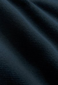 Geweven stof in diep marineblauw met een gestructureerd oppervlak en verhoogde patronen, met subtiele groeven en een zachte, flexibele uitstraling.
