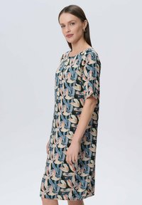 Kleid mit Blumenmuster, lockerem Schnitt, runder Ausschnitt, kurzen Ärmeln und knielanger Länge. Der Stoff zeigt verschiedene Farben, darunter Blau, Pink und Beige.