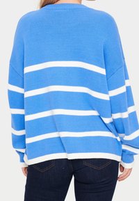 Pull rayé bleu avec des rayures horizontales blanches, coupe ample, encolure et ourlet côtelés, tricot texturé, associé à un jean foncé.