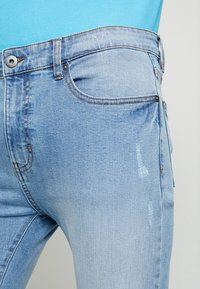 Ljusblå denimjeans med slim fit, med en femfickdesign, sömdetaljer och en lätt blekt textur.