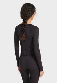 Schwarzes, langärmeliges, figurbetontes Oberteil mit glatter, weicher Textur. Verfügt über Nahtdetails und einen abgerundeten Ausschnitt, geeignet für sportliche Aktivitäten.