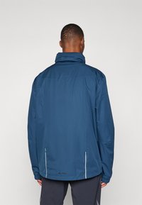 Zila ūdensizturīga jaka ar augstu apkakli, elastīgu piedurkņu galos un atstarojošiem akcentiem. Ir logo apakšējā malā un plaša piegriezuma dizains.