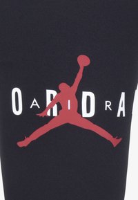 Tessuto nero con un grande logo rosso "Jumpman" e testo bianco. Texture liscia con un design sportivo adatto all'abbigliamento sportivo.