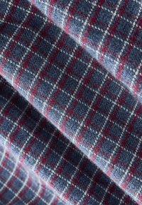 Tissu en laine douce avec un motif à carreaux bleu, rouge et blanc, plié pour montrer la texture et les détails.