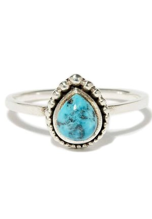 Srebrny pierścionek z niebieskim turkusowym kamieniem w kształcie łzy, otoczonym małymi srebrnymi koralikami na cienkiej obrączce.