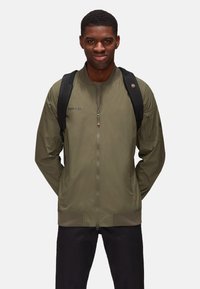 Giacca bomber verde oliva con zip frontale, polsini a coste e dettagli con logo. Realizzata in tessuto liscio e leggero. Spallacci neri per lo zaino.