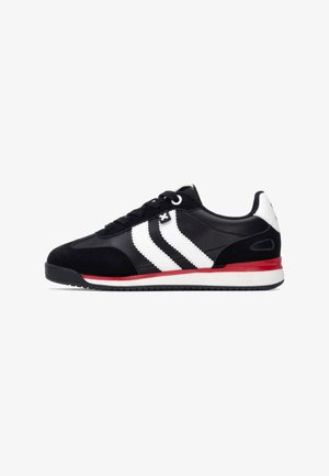 Zapatillas deportivas negras con franjas blancas, material de ante y sintético, diseño de cordones, acentos rojos en la suela, suela de goma plana.