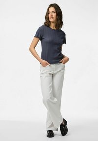 Marinblå ribbad stickad topp med fransade korta ärmar, kombinerad med vida vita byxor och svarta polerade loafers.