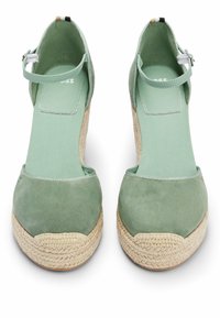 Paire de chaussures espadrilles compensées en daim vert avec brides à la cheville et semelles en jute tressée, vues de face sur fond blanc.