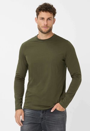 Langärmliges T-Shirt in Olivgrün mit Rundhalsausschnitt und glattem Baumwollgewebe. Modell trägt es zu dunklen Jeans.