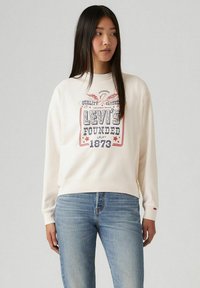 Felpa bianca con collo a giro e stampa grafica rossa e blu che presenta la scritta "Levi's Founded 1873". Composta da un mix di cotone, con maniche lunghe e orlo a costine.