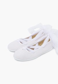 White ballet shoes with a textured surface, featuring crisscross straps and large tulle bows at the back, set against a plain background.