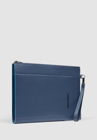 Clutch de cuero azul con una textura suave, que cuenta con un cierre de cremallera, una correa para la muñeca y un diseño minimalista con acentos de hardware plateado.