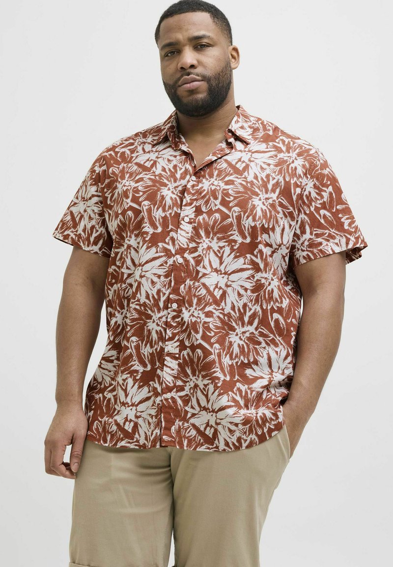 Rövid ujjú gombos ing téglavörös színben, fehér virágmintával; könnyű anyagból készült; laza szabású; hegyes gallér; egy elülső zseb.