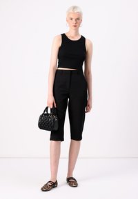 Black ribbed crop top, tailored black cropped pants, textured black handbag, and leopard print flats. Simple, modern design with neutral colors.