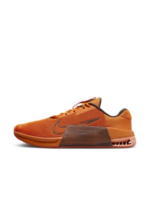 Baskets de sport orange et marron avec tige en mesh, logo Nike, semelle intermédiaire épaisse et détail visible de l'amorti au talon, vues de côté.