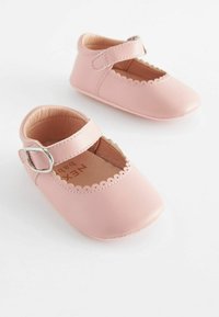 Pink baby shoes made of smooth synthetic material, featuring scalloped edges and a strap with a silver buckle. Rounded toe design.