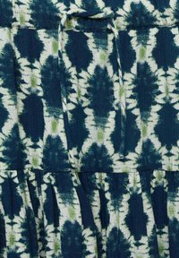 Cotton dress featuring a dark blue and white tie-dye pattern with green accents. The design includes pleats and a waistband tie detail.