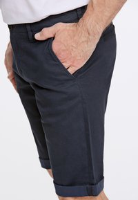 Pantaloni corti in cotone blu navy con una finitura testurizzata, dotati di tasche laterali e orlo arrotolato. Design slim fit con una fascia in vita liscia.