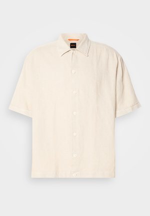 Camisa de lino crema de manga corta con botones en la parte frontal, cuello de punta y corte relajado. Presenta seis botones y una textura mínima.