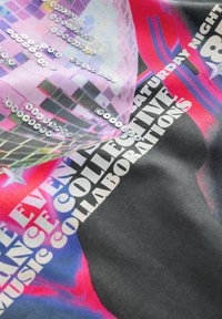 Wielokolorowy materiał z grafiką kuli dyskotekowej, cekinami oraz wyraźnym czarnym i białym tekstem, zawierający wyraziste odcienie różu i purpury.