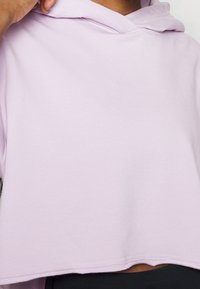 Hoodie corto lavanda in morbido misto cotone con cappuccio regolabile e orlo grezzo. Caratterizzato da una vestibilità rilassata e una texture liscia.