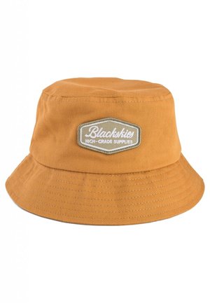 Orange skaterhat lavet af bomuld med en bred skygge. Har et patch med teksten "Blackskies" på en rektangulær baggrund. Syningerne er synlige.
