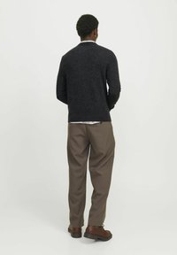Suéter de punto gris oscuro con cuello redondo, combinado con pantalones marrones holgados y zapatos marrones con cordones. Vista posterior.