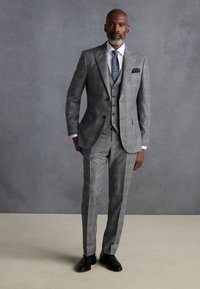 Gray three-piece suit with a checked pattern, featuring a tailored jacket, vest, and slim-fit trousers. Black shoes complete the look.