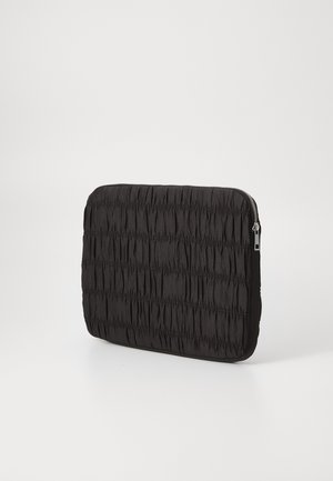 Black padded laptop sleeve with vertical ruching, featuring a smooth texture, rounded corners, and a silver zipper along the top edge.