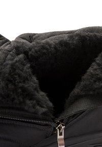 Sort vinterstøvle med tyk, blød foret kant, synlig gennem delvist åben lynlås.