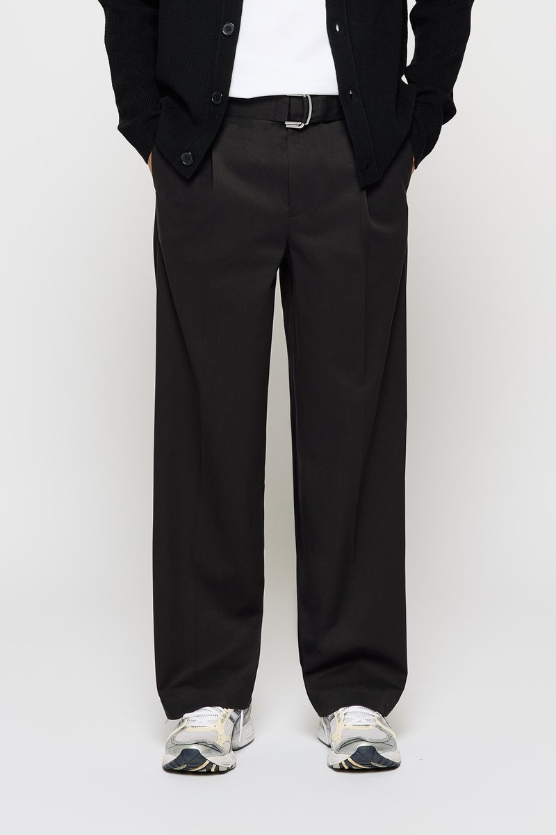 Black, wide-leg trousers with a smooth finish, featuring a flat front and belt loops. Paired with gray and white athletic shoes.
